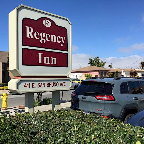 The image shows a sign for Regency Inn located at 411 E. San Bruno Ave. There are cars parked nearby and buildings in the background.